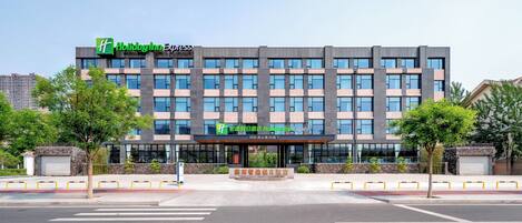 Un hotel Holiday Inn Express con fachada moderna, ventanas grandes y una entrada central.