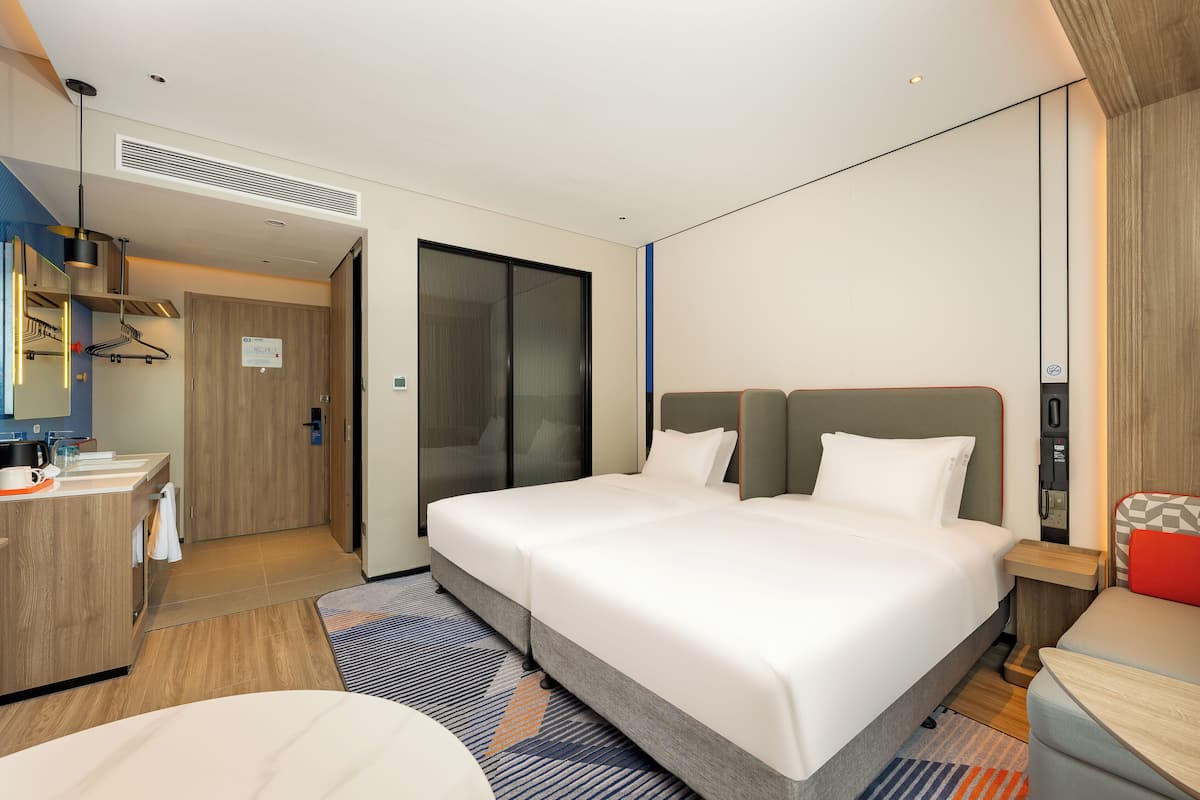 A modern hotel room with a large bed, a desk, and a bathroom.