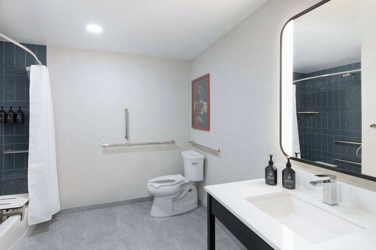 Un baño moderno con un lavamanos blanco, un inodoro, una ducha con cortina blanca y un espejo con marco negro.