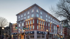 A multi-story building with a brick facade, large windows, and a corner location at an intersection.
