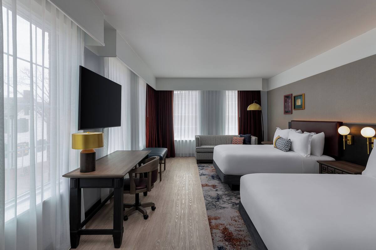 Una habitación de hotel con dos camas, un escritorio, un televisor y un sofá.