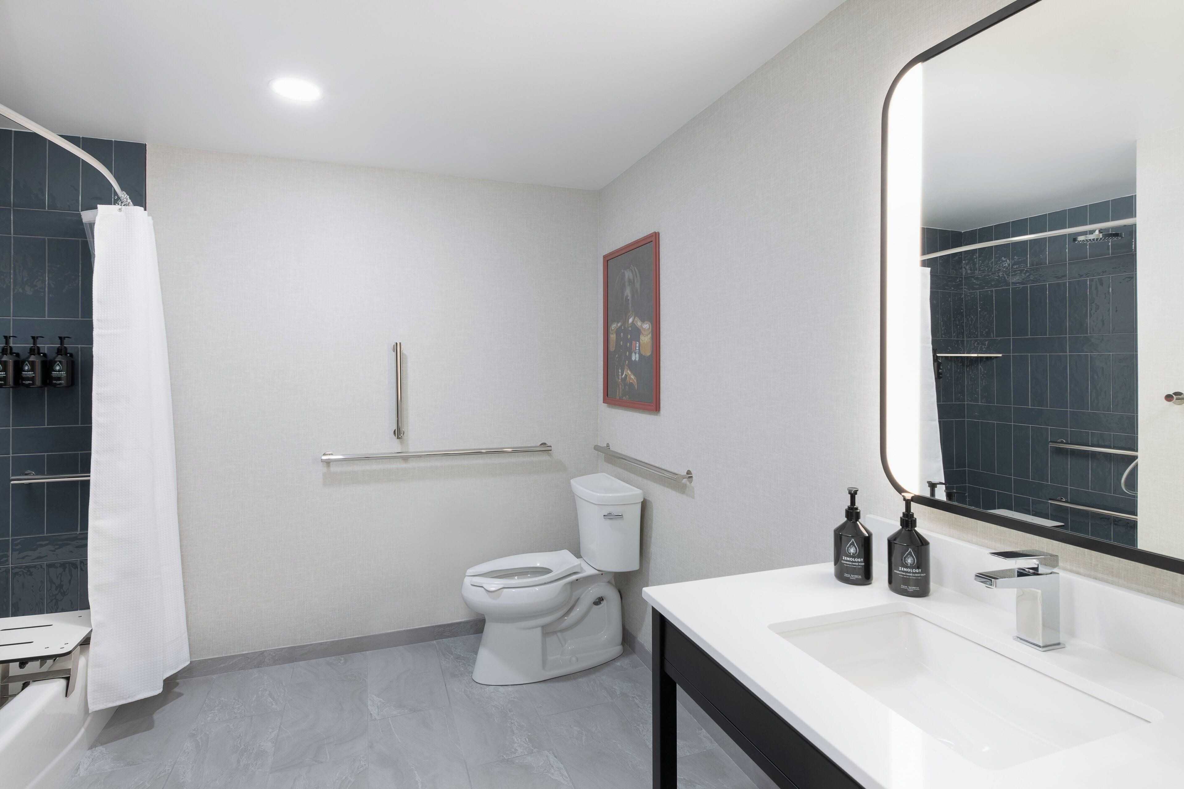 Un baño moderno con un lavamanos blanco, un inodoro, una ducha con cortina blanca y un espejo con marco negro.