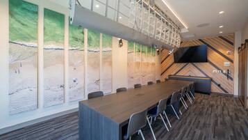 A conference room with a long table, chairs, a TV, and a patterned wall.