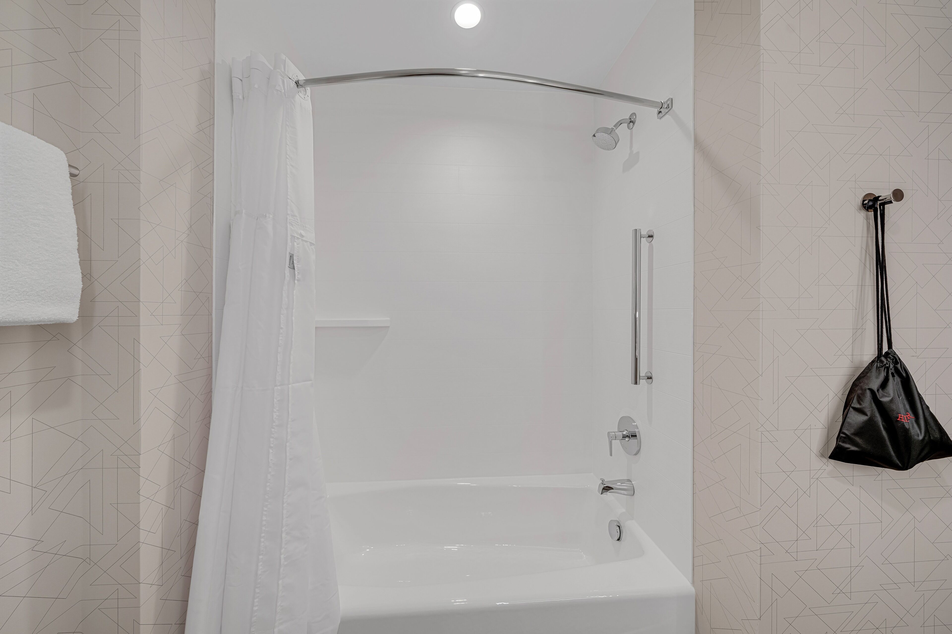 A modern bathroom with a shower, a towel rack, and a hanging bag.