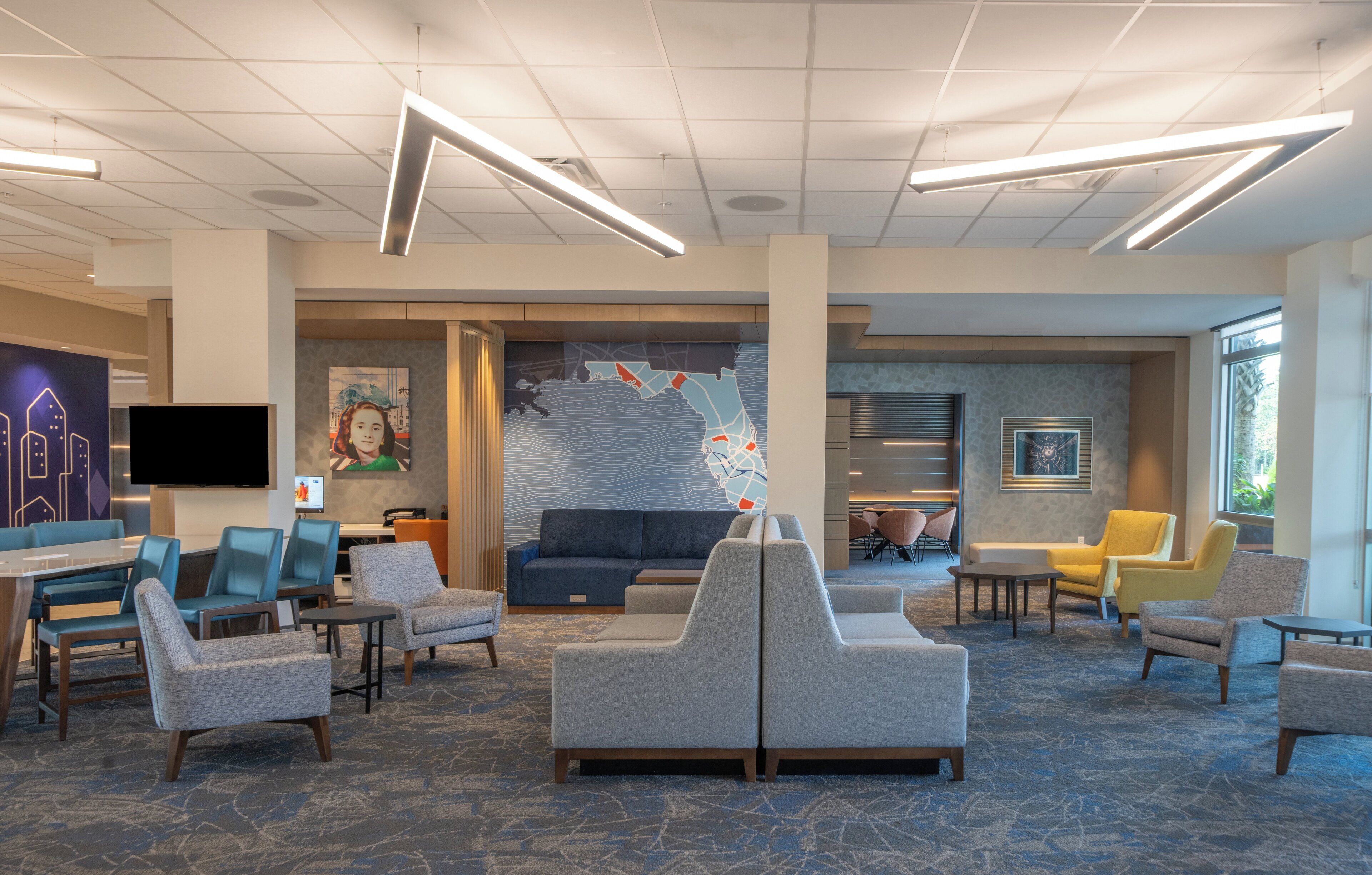 A spacious lobby with seating areas, a flat-screen TV, and a map mural on the wall.