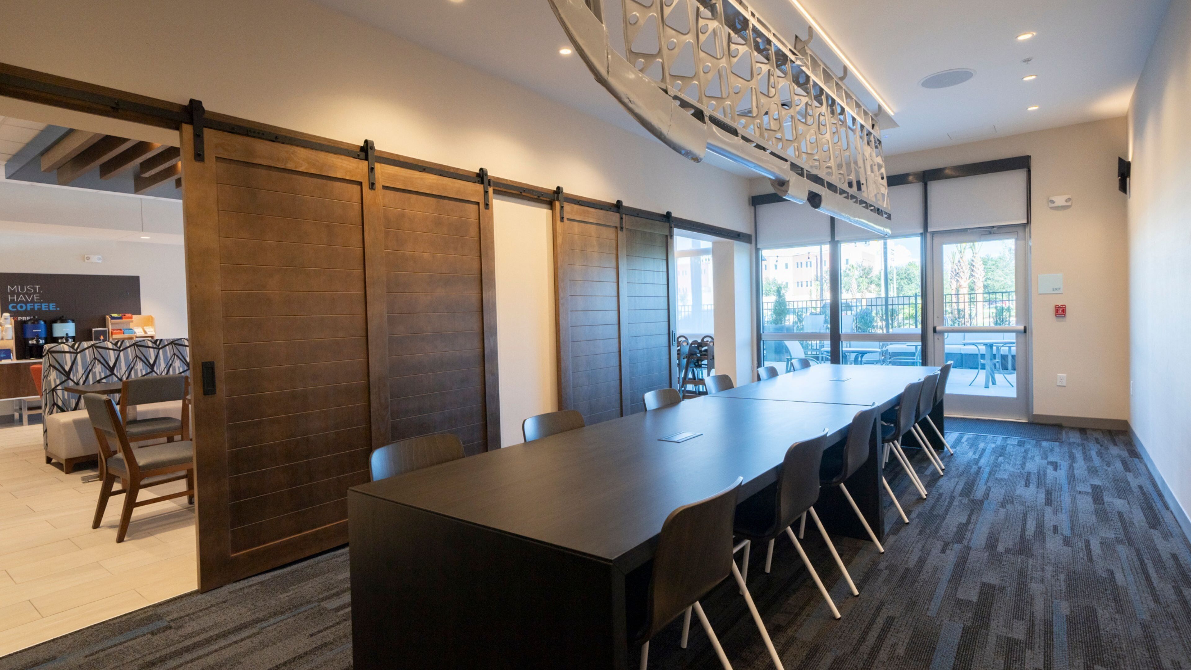 Une salle de conférence avec une longue table, des chaises, un coin café et une vue dégagée grâce à de grandes fenêtres.