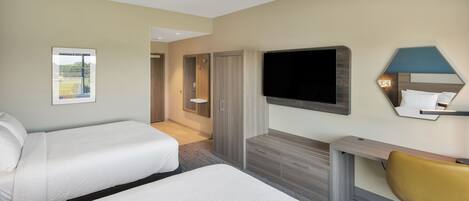 Une chambre d’hôtel avec deux lits, un bureau, une chaise, une télévision et un miroir.