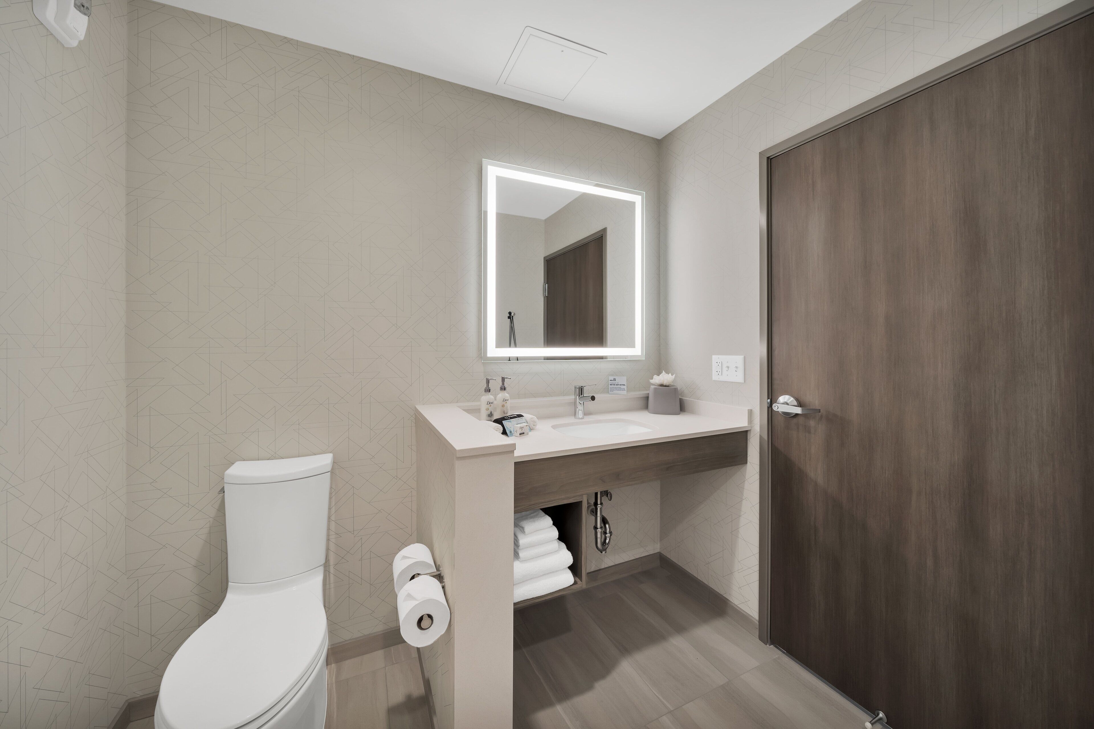 Un baño moderno con inodoro, lavabo y espejo.