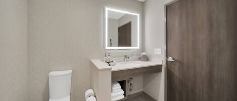 Un baño moderno con inodoro, lavabo y espejo.