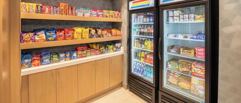 A snack and beverage display area with shelves stocked with various snacks and a refrigerated display case with beverages.