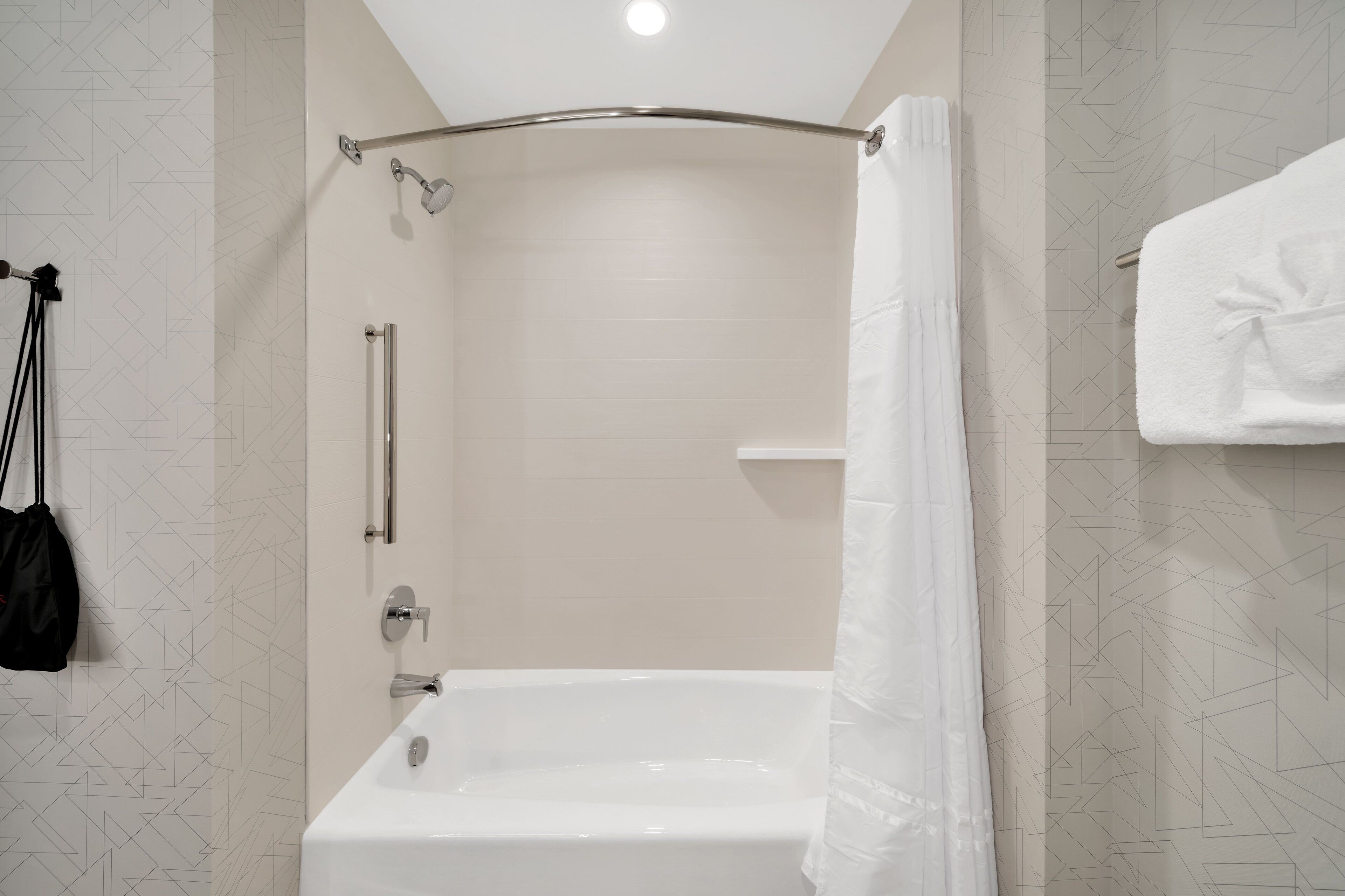 Een moderne badkamer met een bad, douche en een handdoekrek.