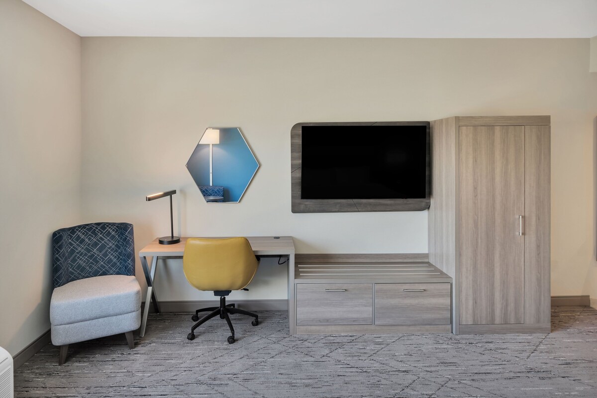 Une chambre d’hôtel équipée d’un bureau, d’une chaise, d’une télévision, d’une armoire et d’une lampe.