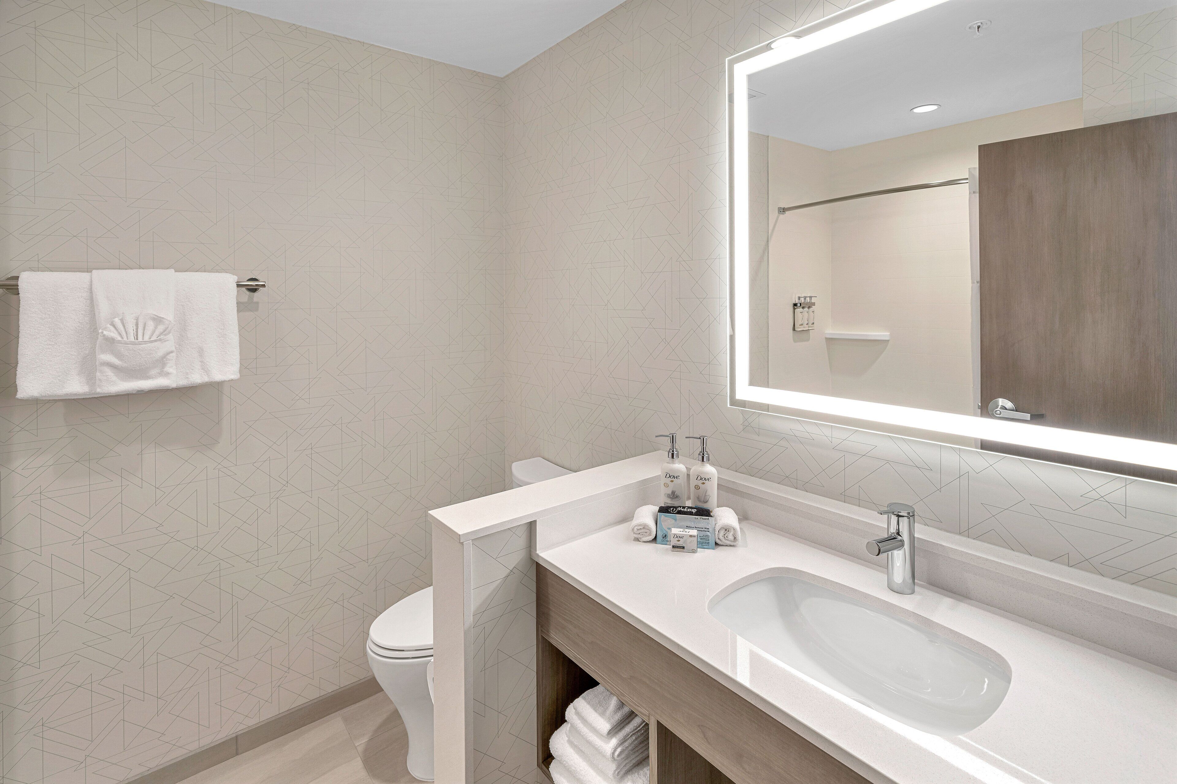 A modern bathroom with a white sink, mirror, and toilet.