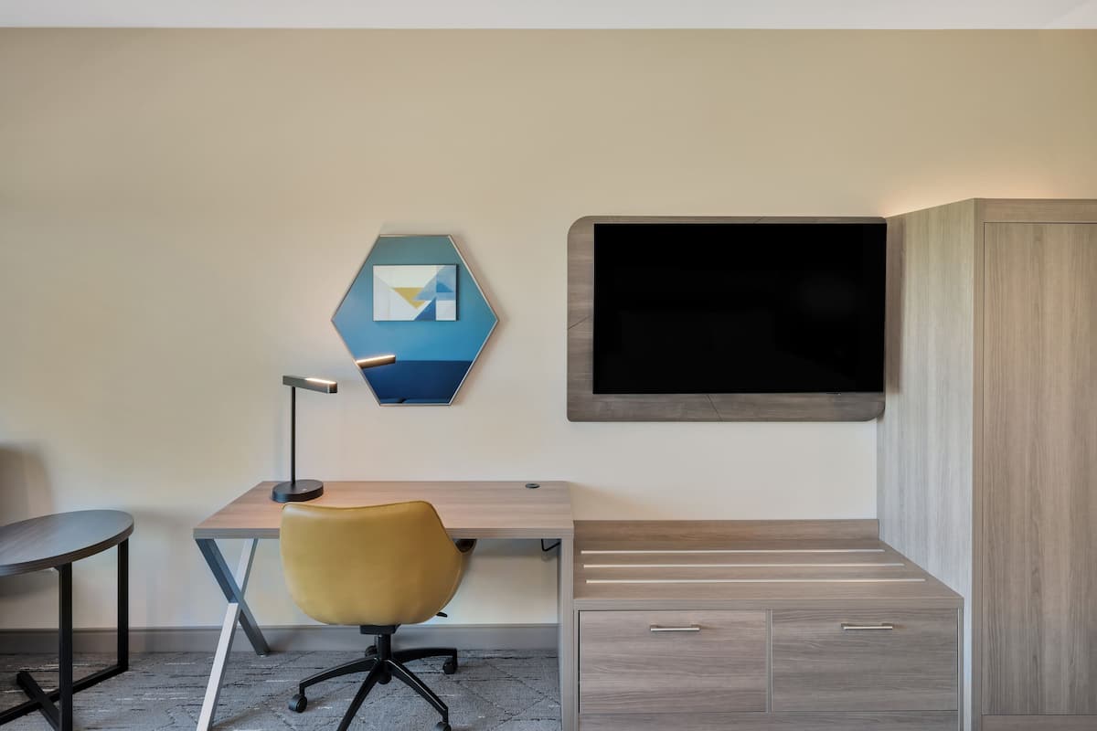 A modern office space with a desk, chair, and a mounted TV.