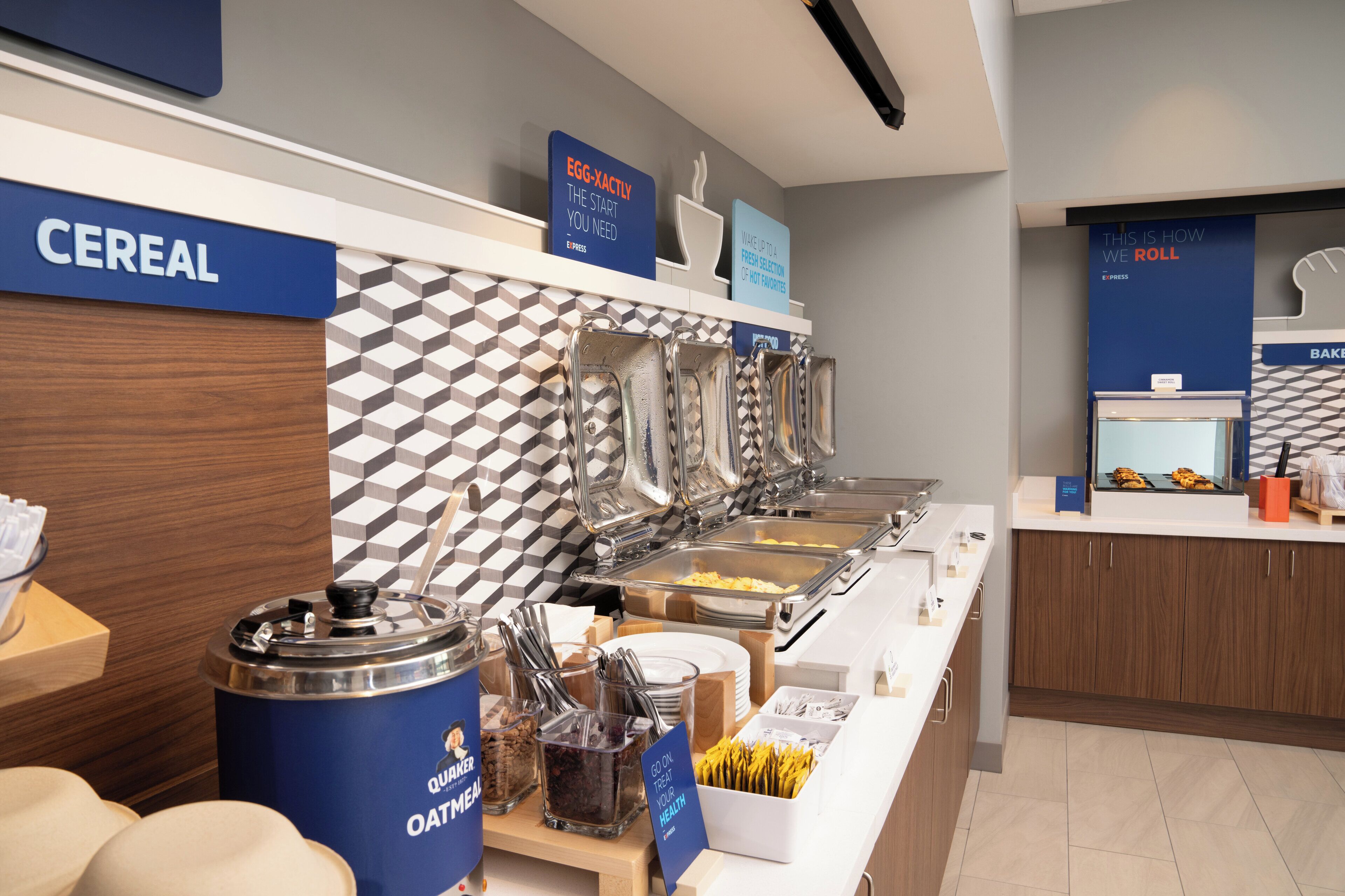 Zona de buffet con secciones identificadas para cereales, huevos y otros productos para el desayuno.
