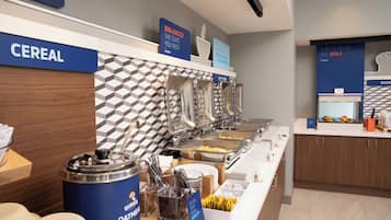 Zona de buffet con secciones identificadas para cereales, huevos y otros productos para el desayuno.