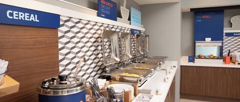 A buffet area with labeled sections for cereal, eggs, and other breakfast items.