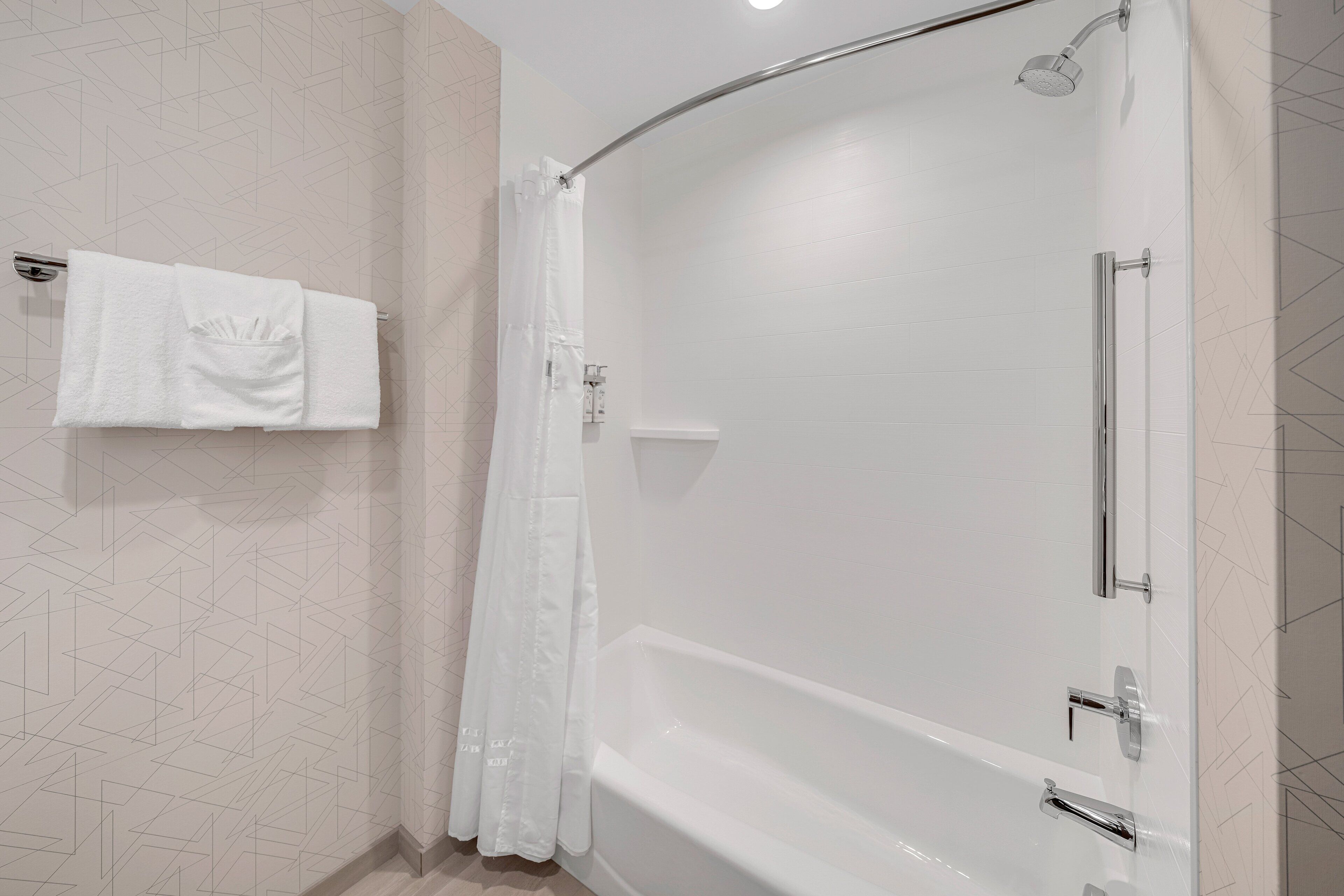 Un bagno moderno con cabina doccia a forma di arco, una vasca e un portaservizi con due asciugamani.