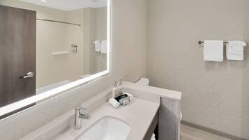 A modern bathroom with a large mirror, a sink, and two towels hanging on a towel rack.