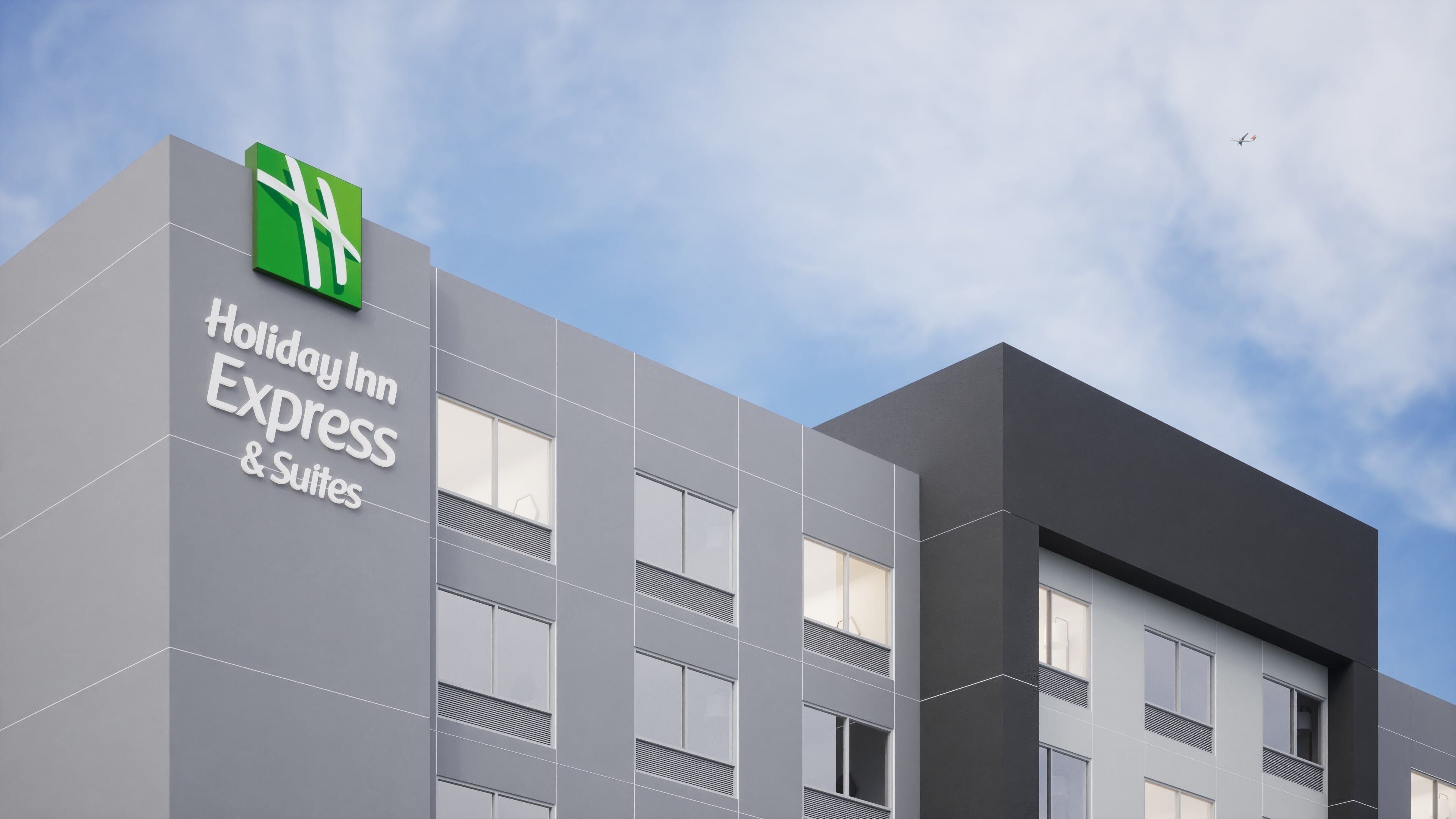 A Holiday Inn Express & Suites building with a modern design, featuring large windows and a prominent logo.