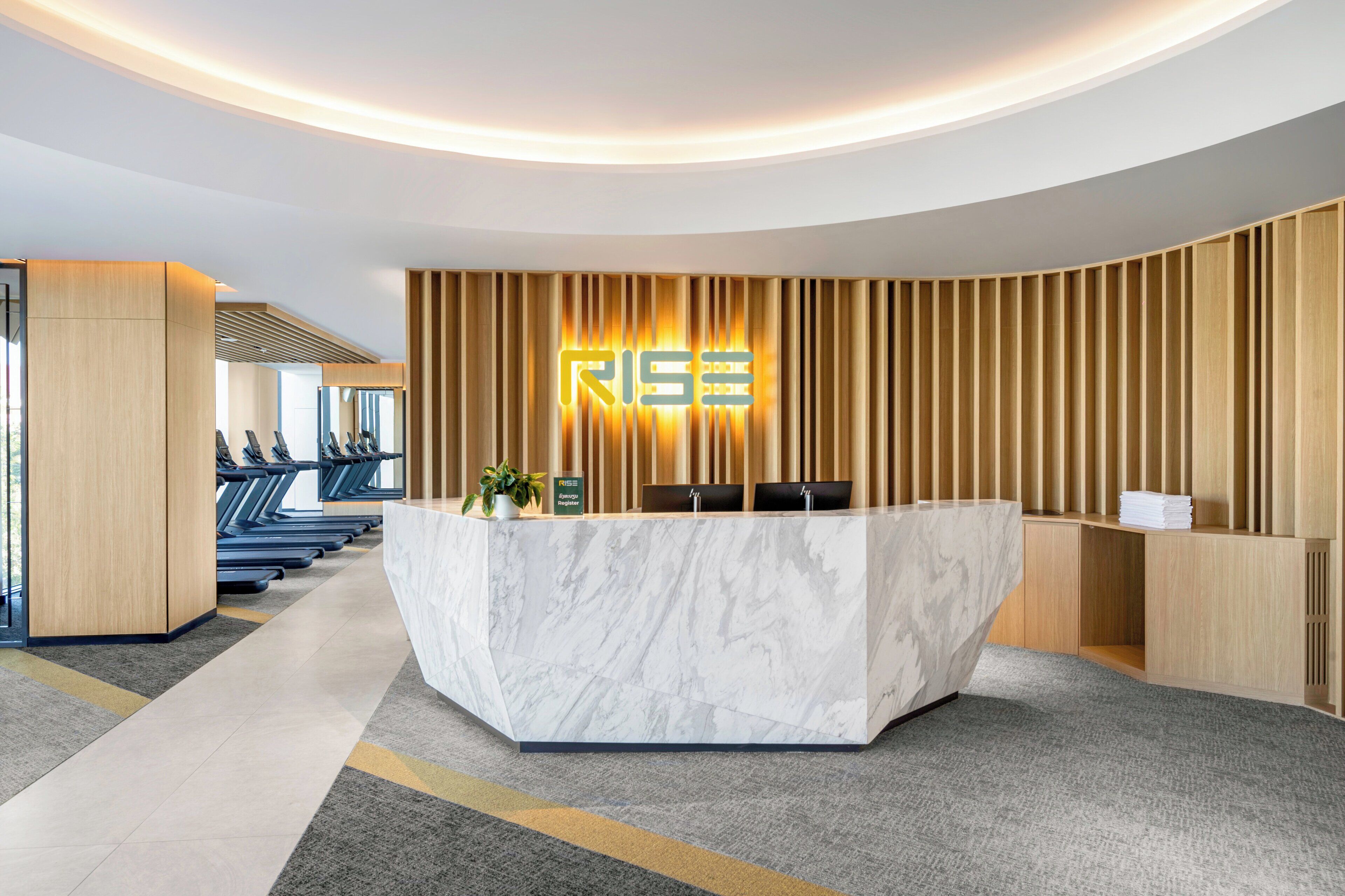A reception desk with a marble top, a wooden panel wall, and a neon sign.