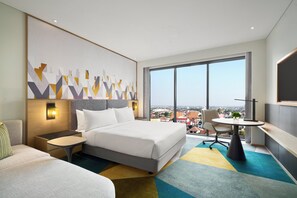 Habitación de hotel moderna con una cama grande, un escritorio y vistas a la ciudad.
