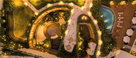 Vista aérea de um átrio de hotel com uma escadaria espiral central, piscina e áreas de estar ao ar livre.