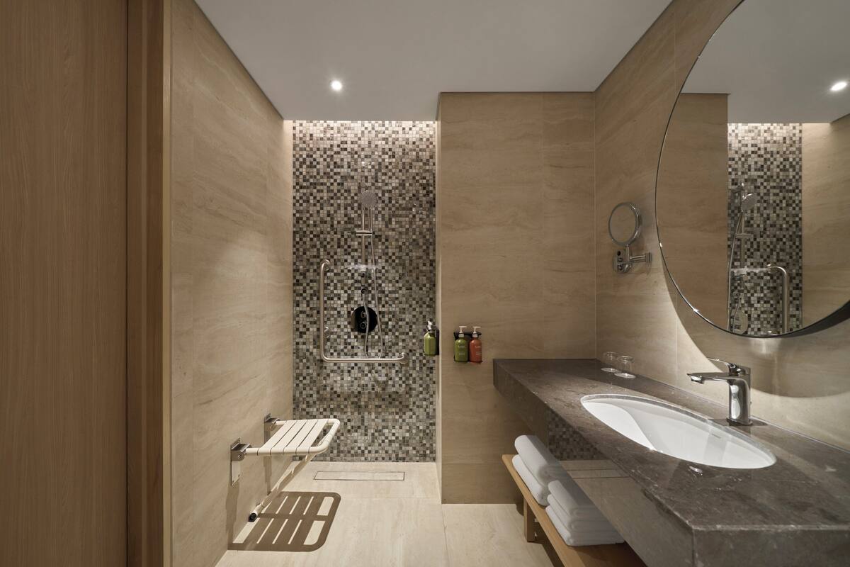 A modern bathroom with a large sink, a mirror, and a shower area.