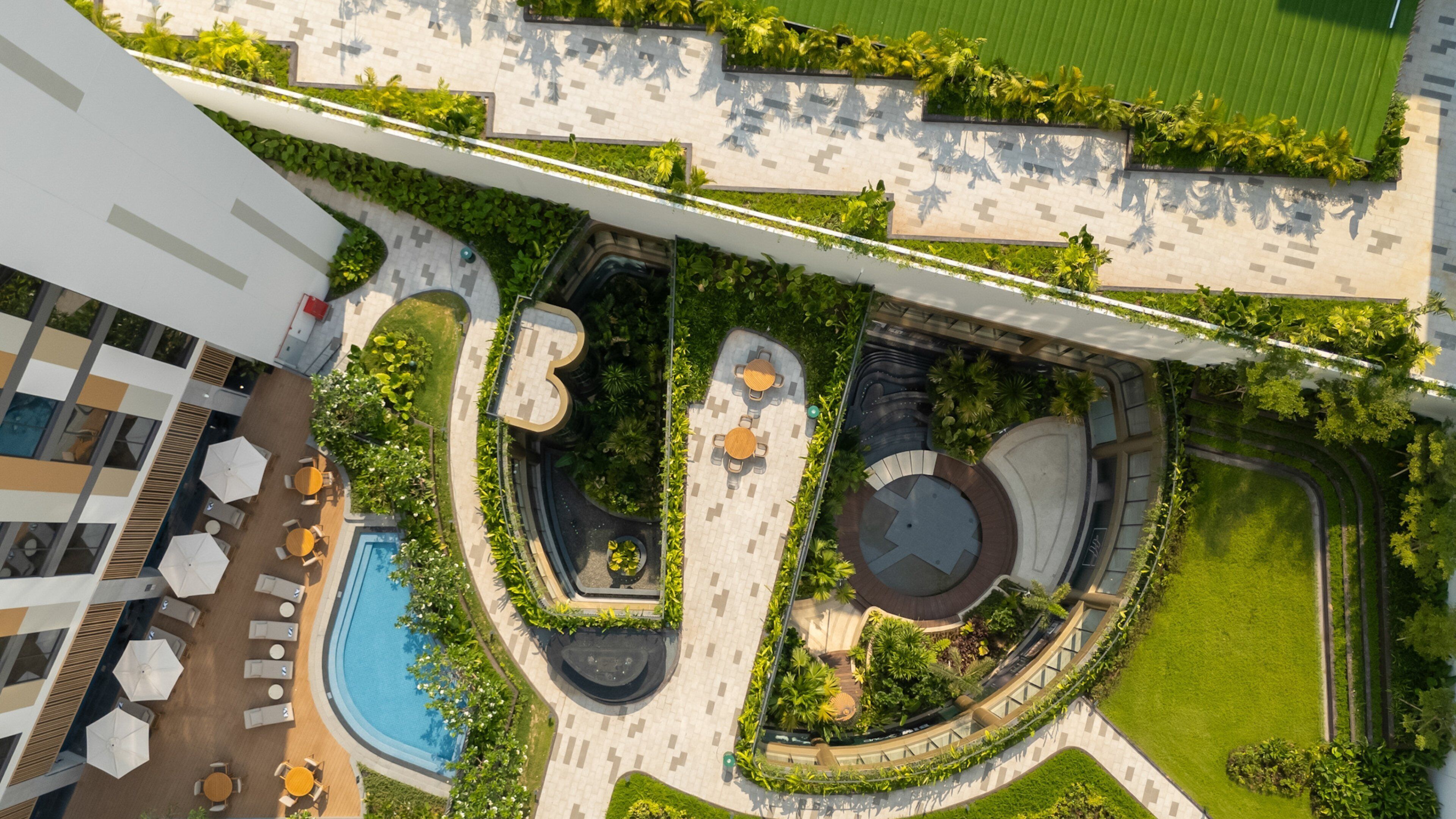 An aerial view of a resort with a swimming pool, outdoor seating areas, and landscaped gardens.