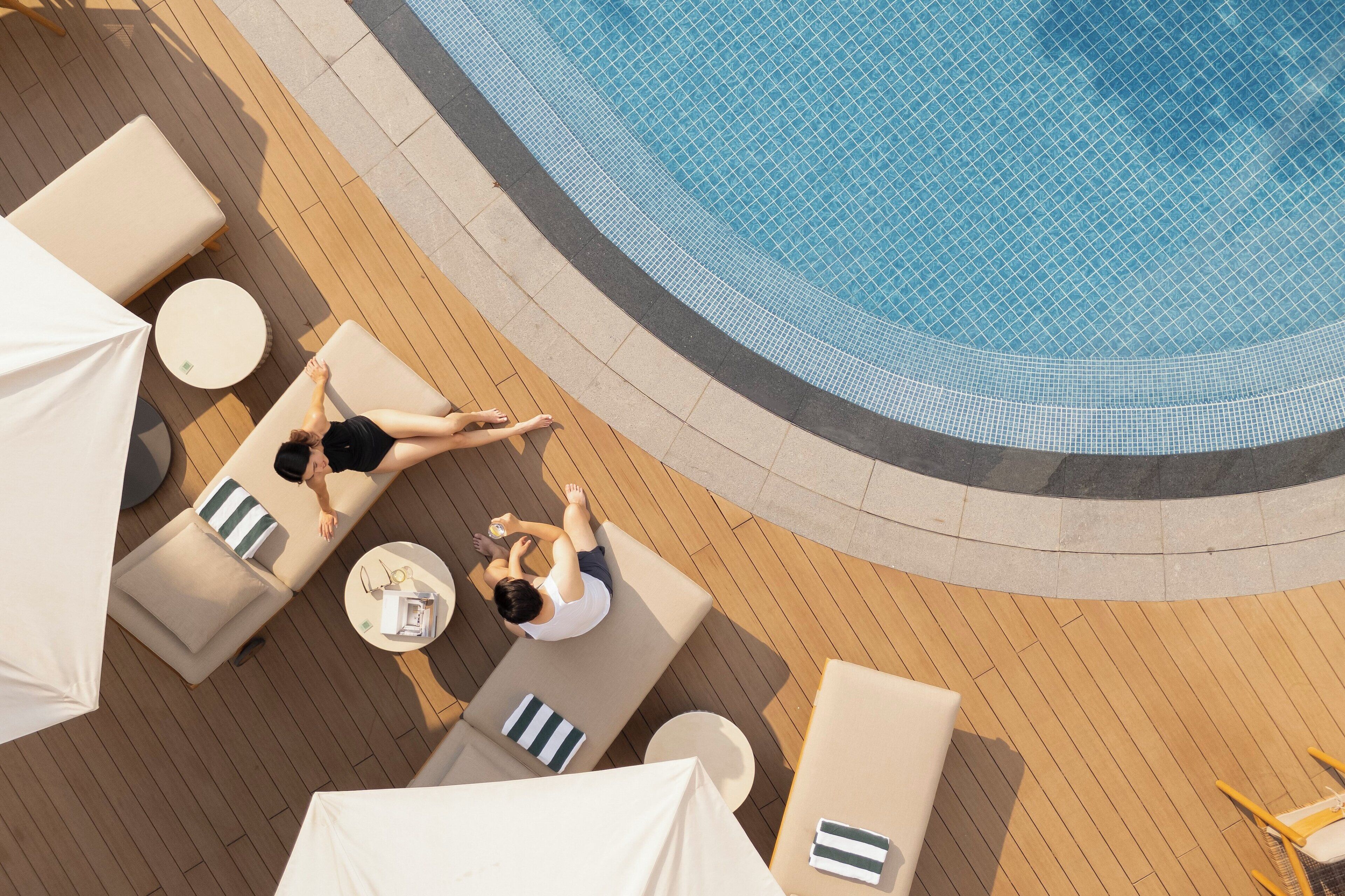 A rooftop pool area with lounge chairs and umbrellas.