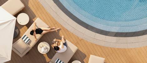 A rooftop pool area with lounge chairs and umbrellas.