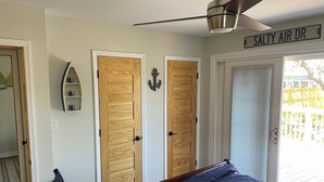 A bedroom with a bed, two wooden doors, a ceiling fan, and a sign reading "SALTY AIR DR". - Gorgeously remodeled Seaside Oasis in Atlantic Beach! (Atlantic Beach)
