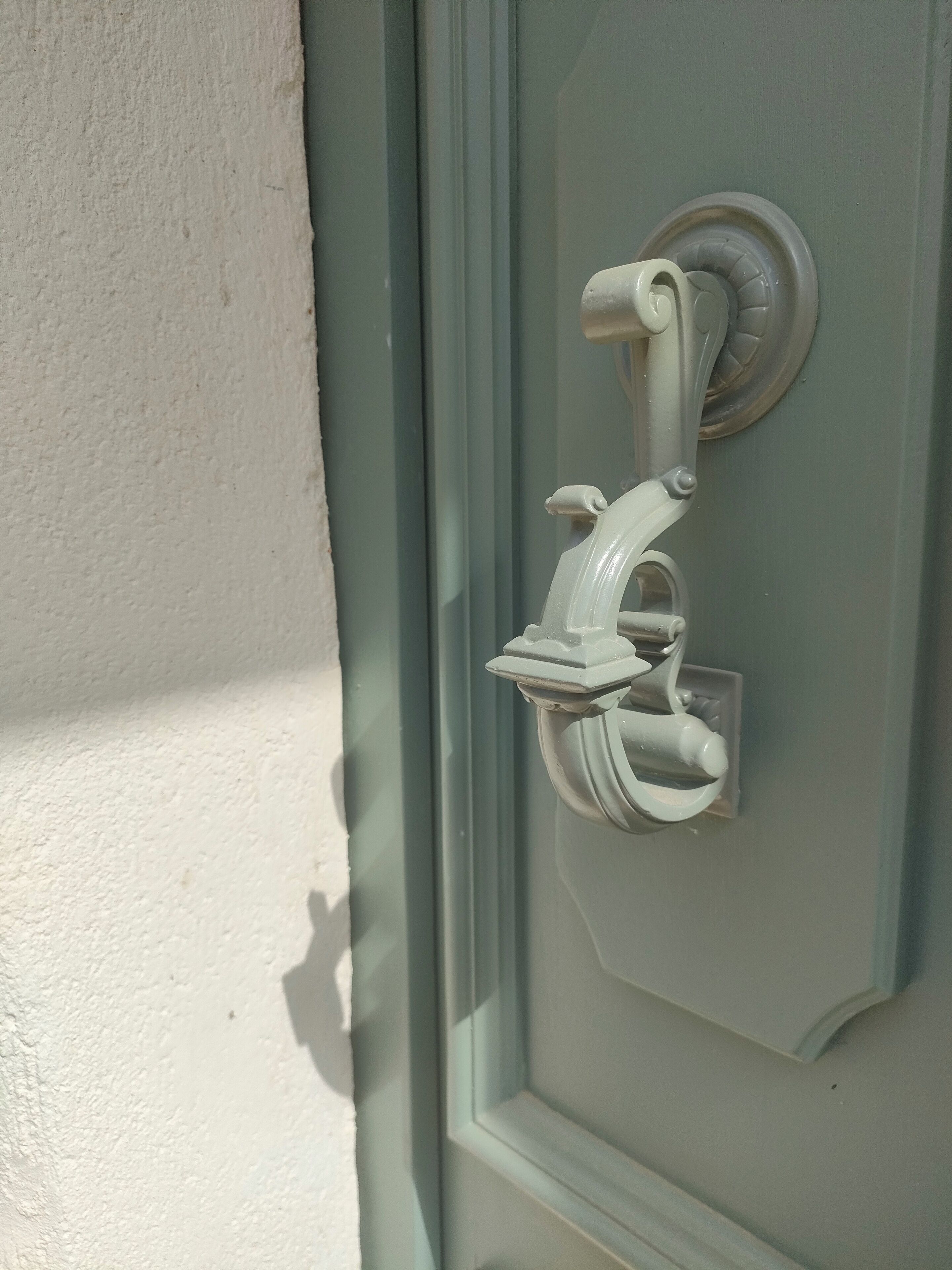 Una puerta con picaporte blanco y placa de cerradura redonda y con textura.