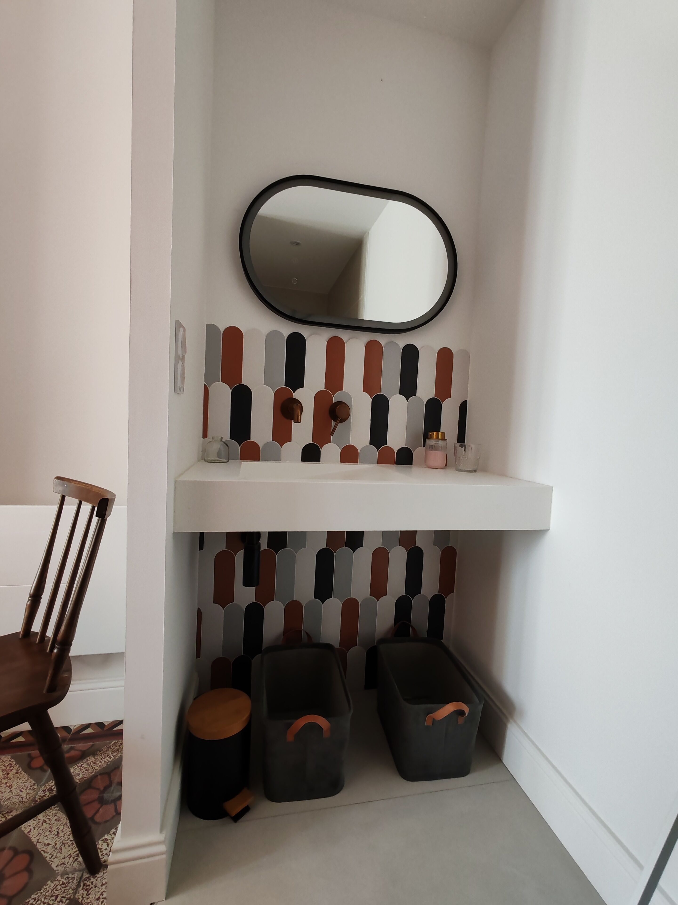 A corner with a white wall, a mirror, a shelf with toiletries, and storage bins.