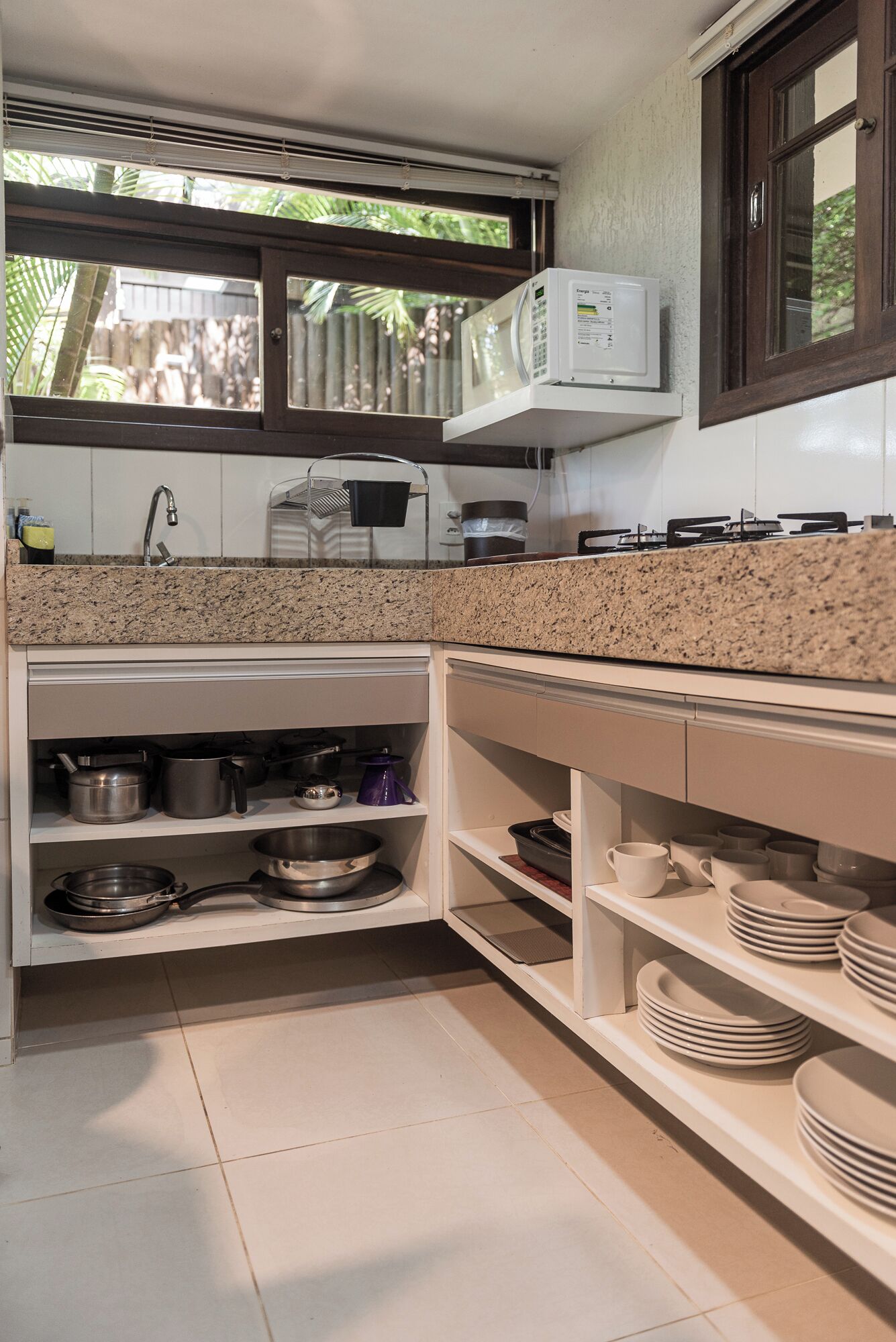 A kitchen with granite countertops, white cabinets, a microwave, and a gas stove.
