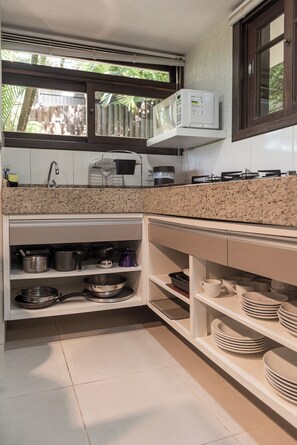 Una cocina con encimeras de granito, armarios blancos, microondas y estufa a gas.