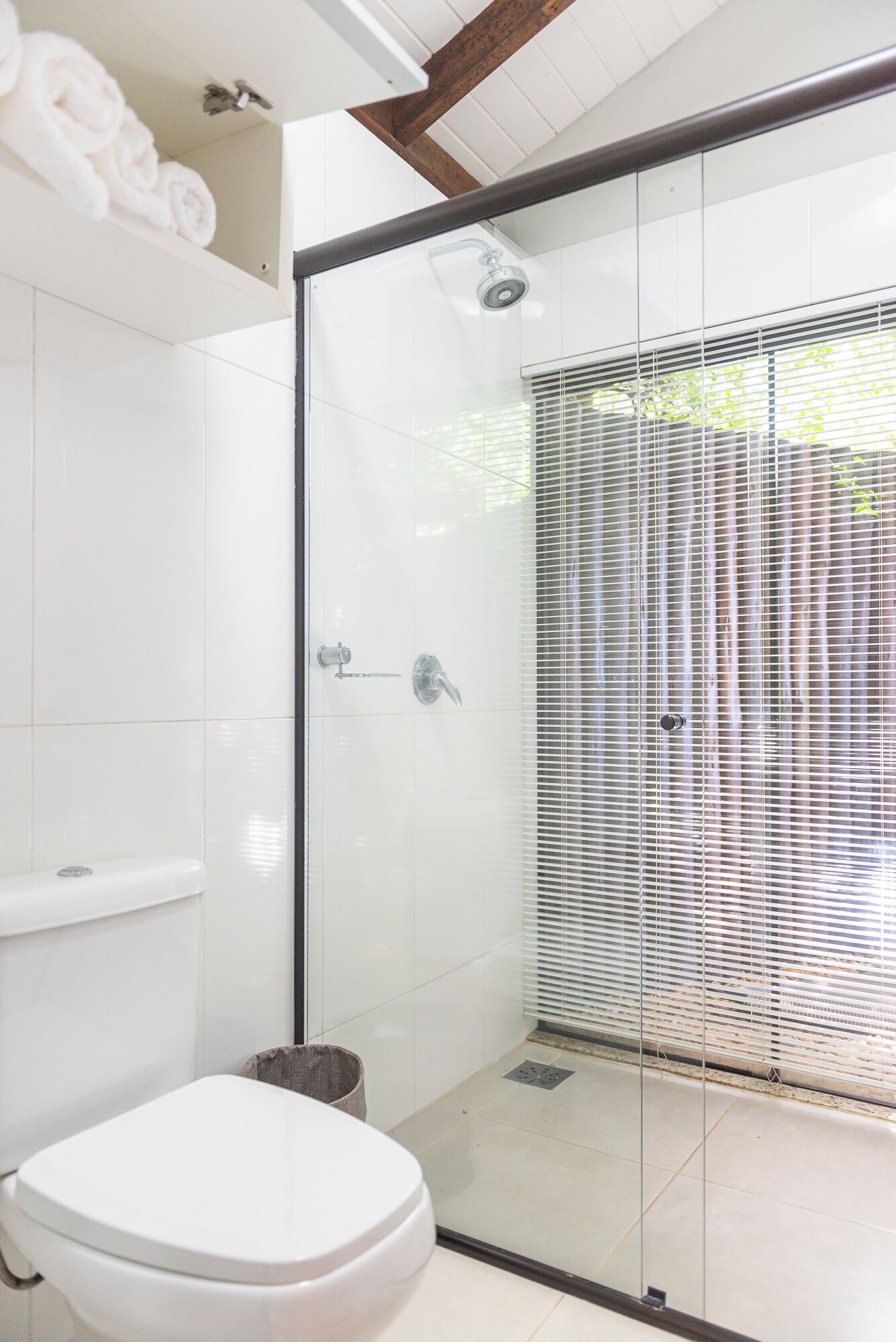 A modern bathroom with a glass shower enclosure, a toilet, and a towel rack.