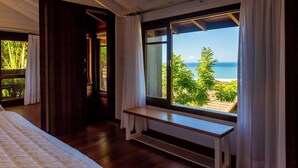 A bedroom with a large window offering a view of the beach and ocean. - Morada Prainha (Garopaba)