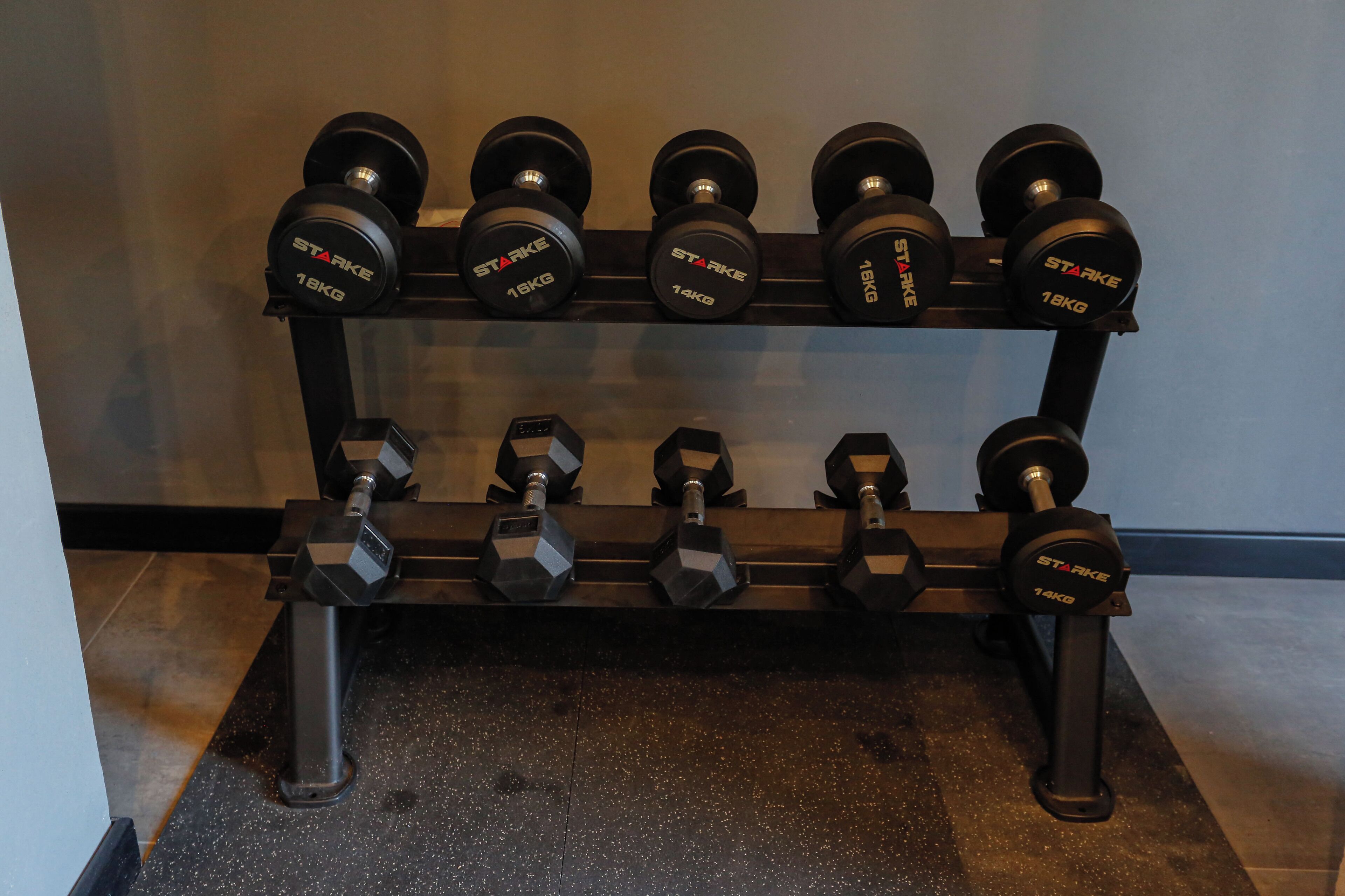 Un ensemble d’haltères, rangés sur un support, avec des poids allant de 10 kg à 18 kg.