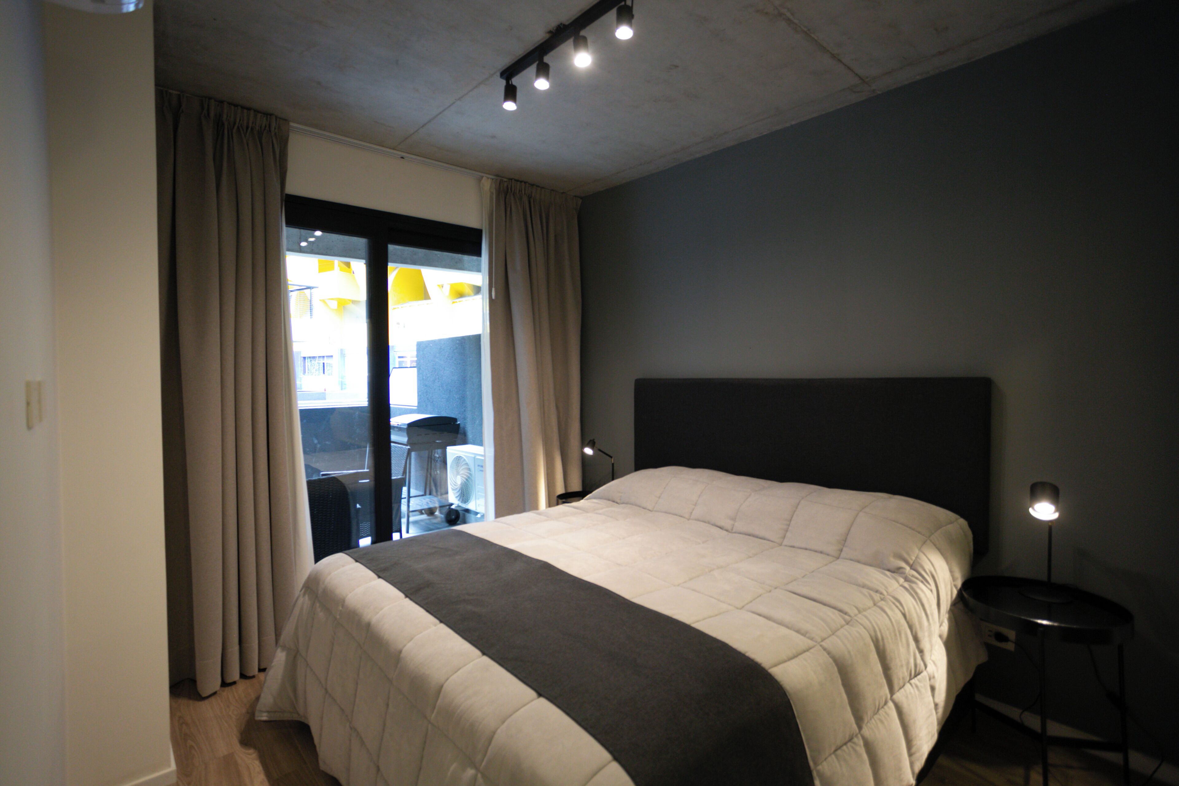 Un dormitorio con una cama grande, un escritorio y una silla cerca de una ventana.
