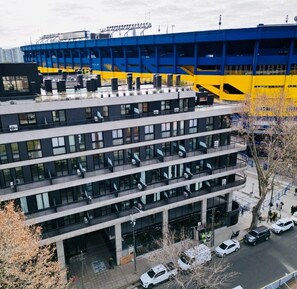 Un immeuble à plusieurs étages doté d’une architecture moderne, caractérisé par une série de balcons et de grandes fenêtres.