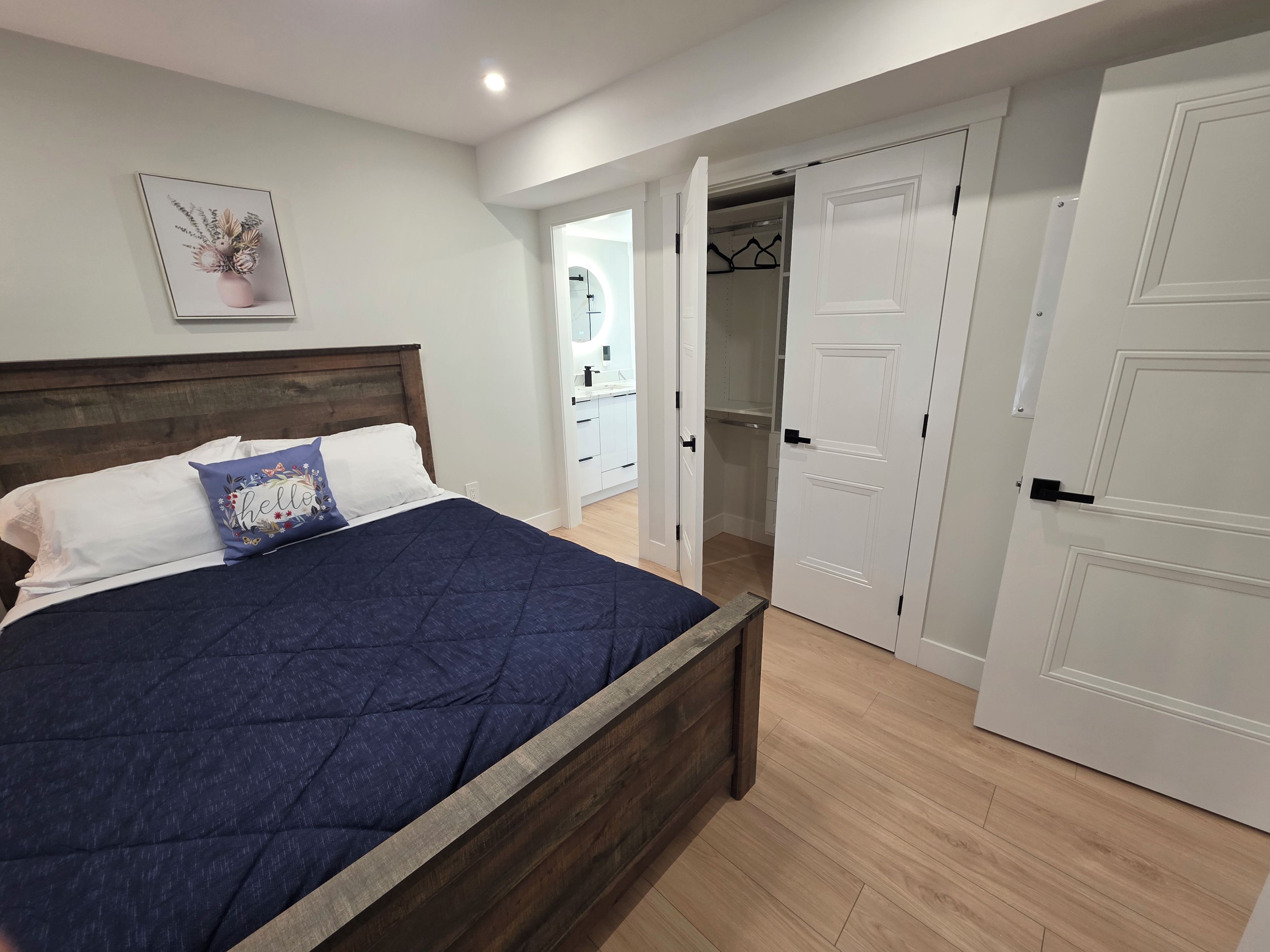 Un dormitorio con cama, armario y baño visible a través de una puerta abierta.