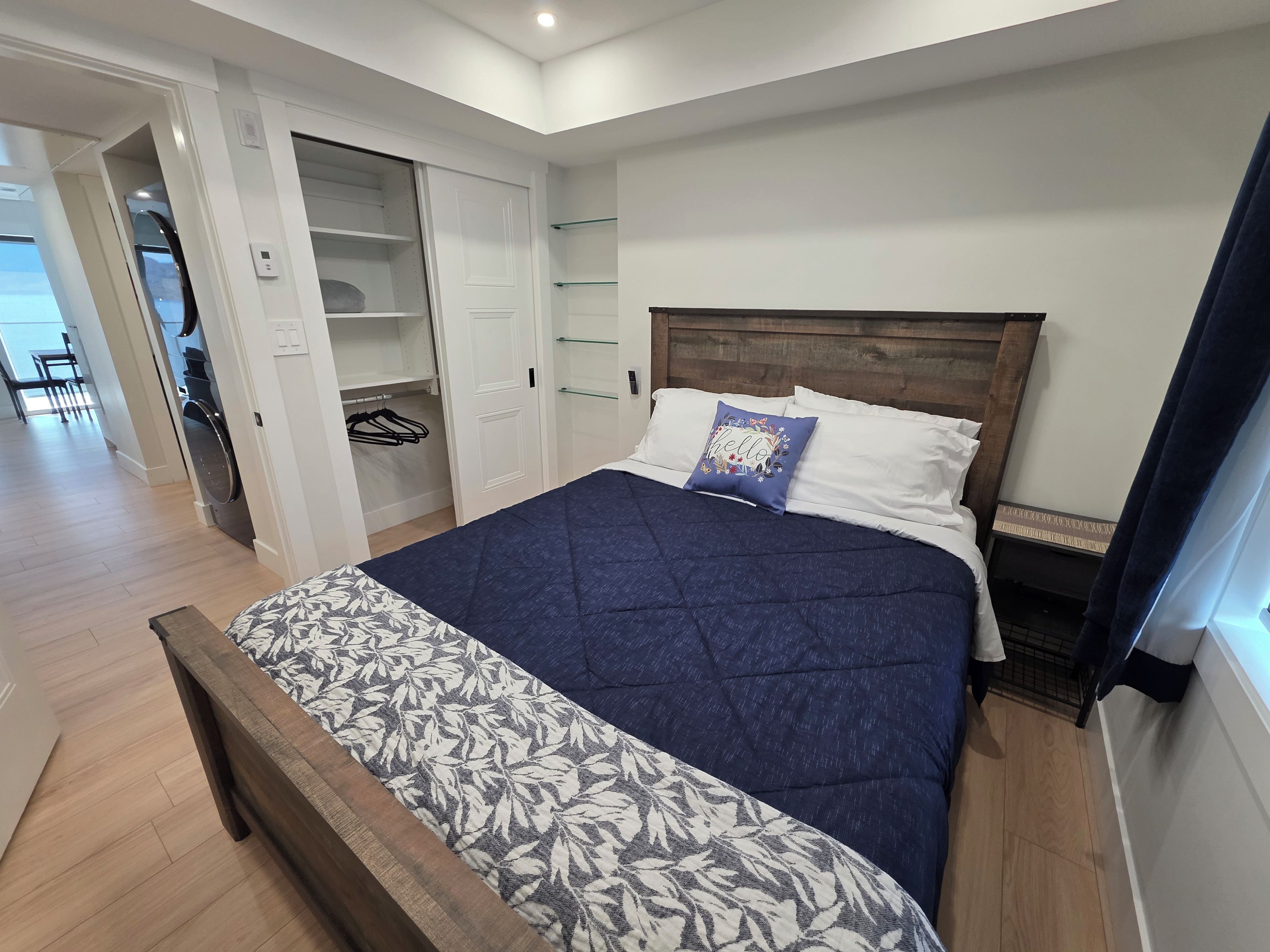 Un dormitorio con cama, cabecero de madera, armario con espacio para colgar y mesita de noche.