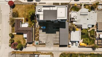 An aerial view of a commercial building with a parking lot, adjacent smaller buildings, and surrounding greenery.