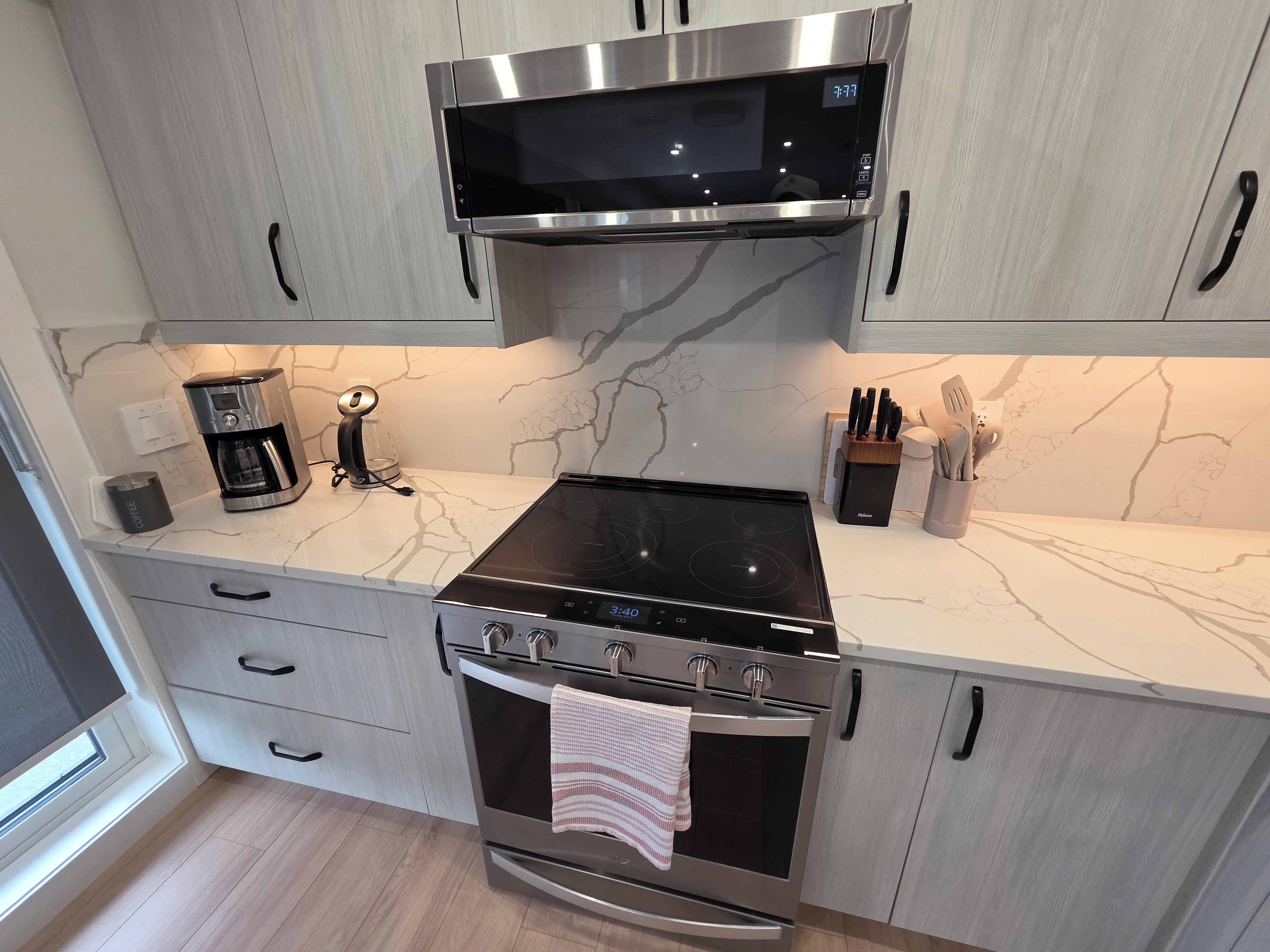 Une cuisine moderne équipée d’un four à micro-ondes, d’une cuisinière, d’un four et d’une machine à café encastrés.