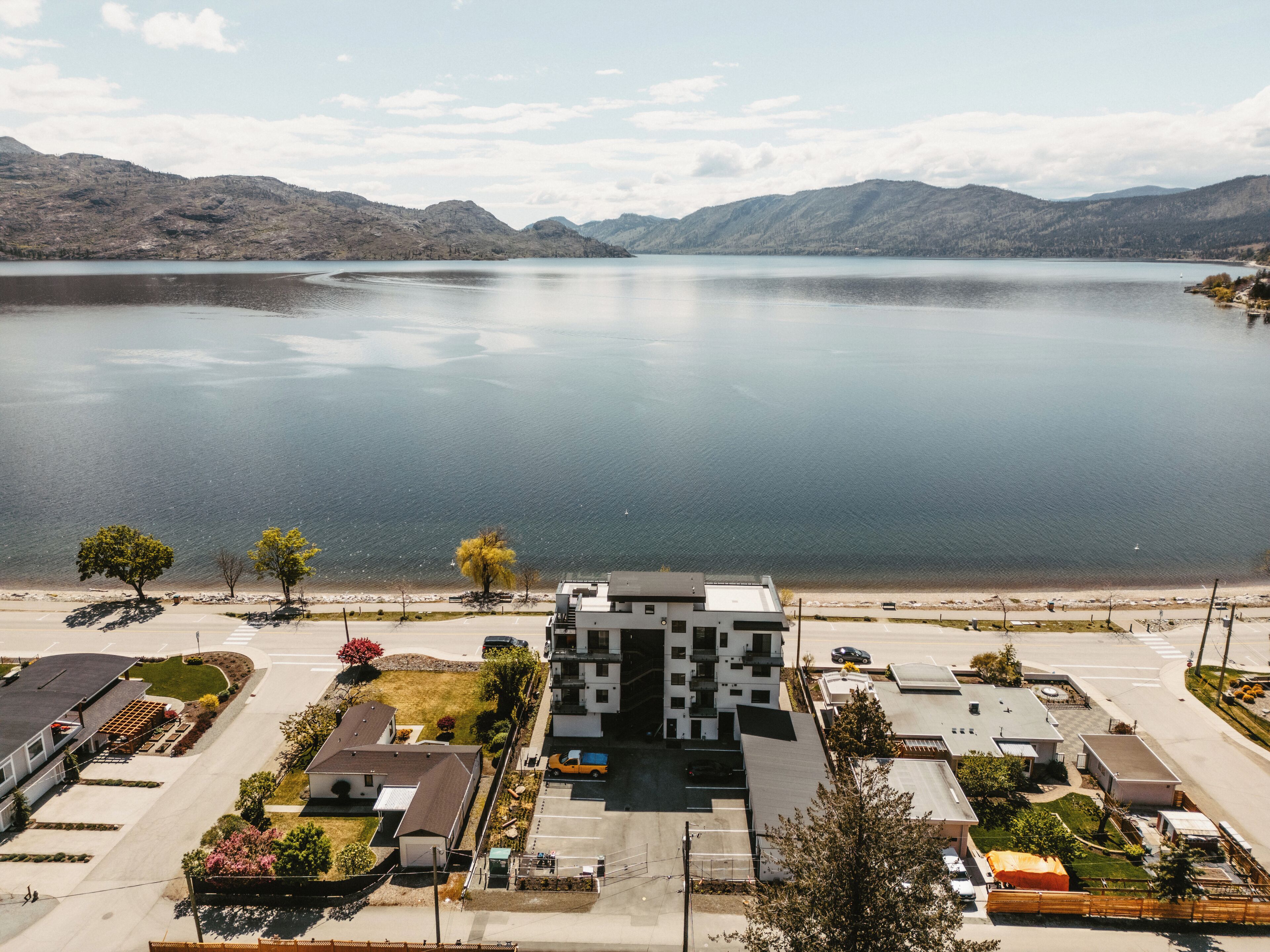 Un edifici modern amb teulada plana, envoltat d'un aparcament i un llac.