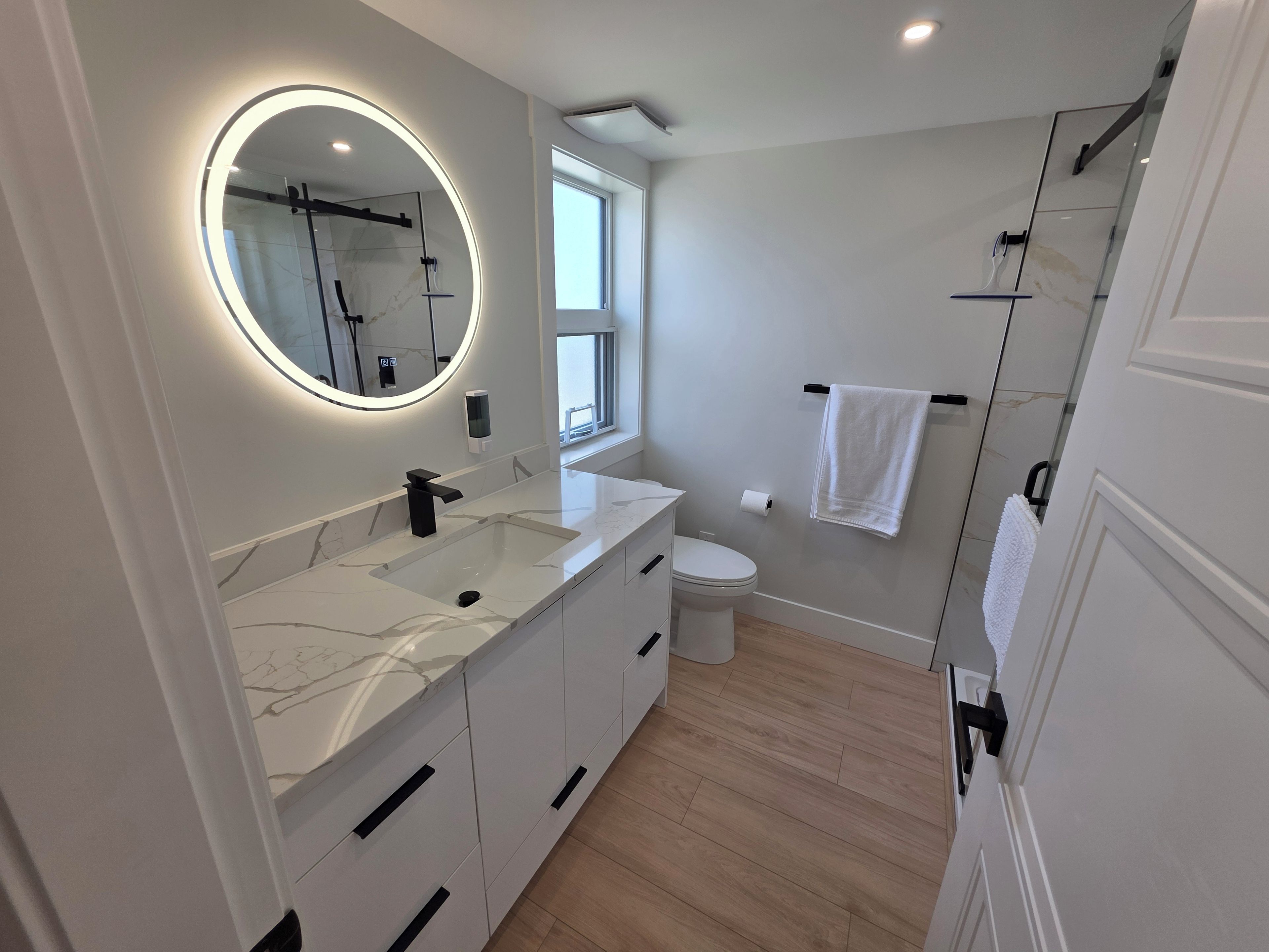 Une salle de bain moderne avec un lavabo en marbre, des toilettes et une douche à parois de verre.