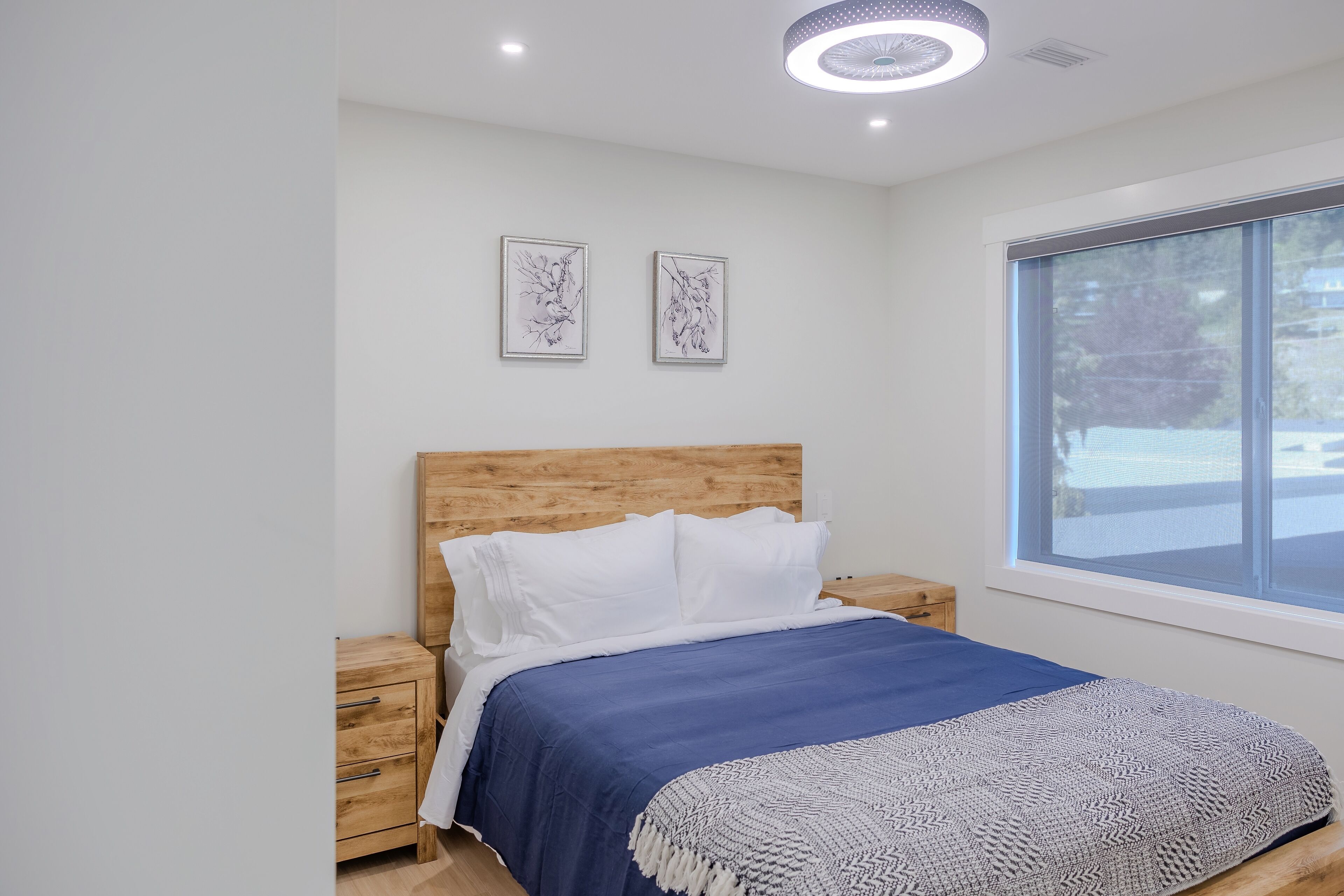 A bedroom with a wooden headboard, a blue bedspread, and two bedside tables.