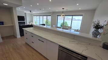 Una cocina moderna con encimera de mármol, lavavajillas integrado y grandes ventanales con vistas al lago.