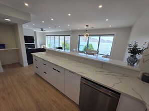 Una cucina moderna con un piano di lavoro in marmo, lavastoviglie integrata e ampie finestre con vista sul lago.